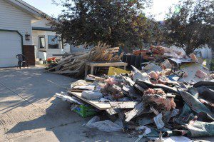 Sodden belongings piled on the street outside of a flood damaged home.