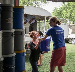 Rebecca Shetler Fast (in blue), MCC country representative, and Elise Quiring (in black), Connecting Peoples coordinator, help to load relief kits from storage onto the truck that will carry the kits to MCC's partner SAKALA in Cité Soleil, a neighborhood in Port-au-Prince. Twenty families are sheltering in SAKALA's community center after flash flooding from Hurricane Matthew forced them from their homes. Some of the families' homes were completely washed away in the storm. MCC Haiti provided relief kits, blankets, water purification and food to them. (MCC photo/Paul Shetler Fast)