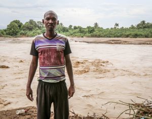 Hudson Reny-Jean stand beside the River Gris that washed away homes in the Voudray community of Cite Soleil. The flooding also affected the safety of drinking water, making the water purification tablets that MCC provided a blessing, according to Reny-Jean.“He held these 3-cent tablets in his hand and just kept repeating, ‘These are such a blessing, these are such a blessing for our community." (MCC photo/Paul Shetler Fast)